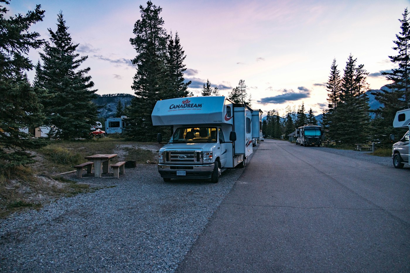 Motorhome parked at a forest campground at dusk